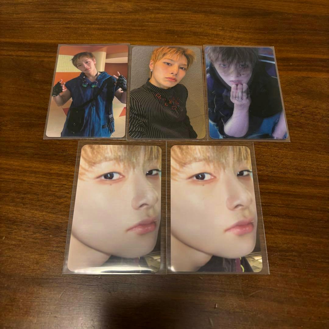 Five Stray Kids THIS&THAT photocards arranged on a wooden surface showing portrait photos of the member I.N.