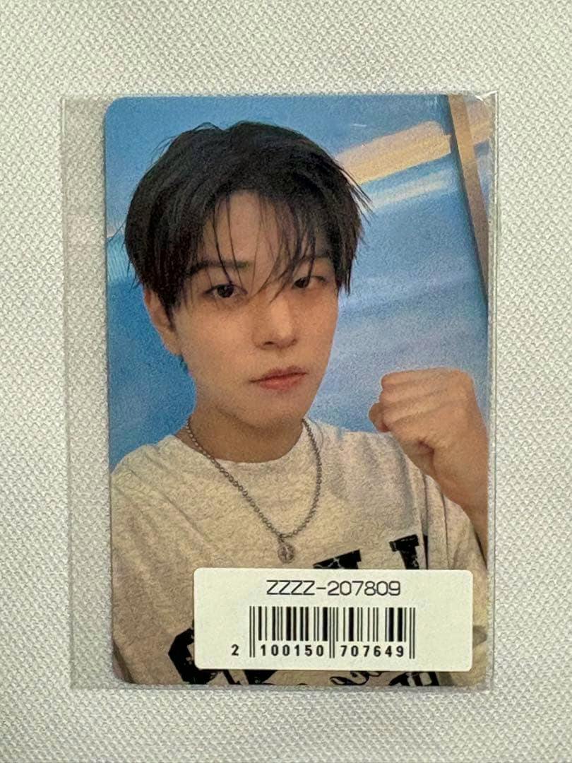 Front of the photocard showing a person's portrait wearing a white shirt and silver necklace with a barcode sticker on the lower area.