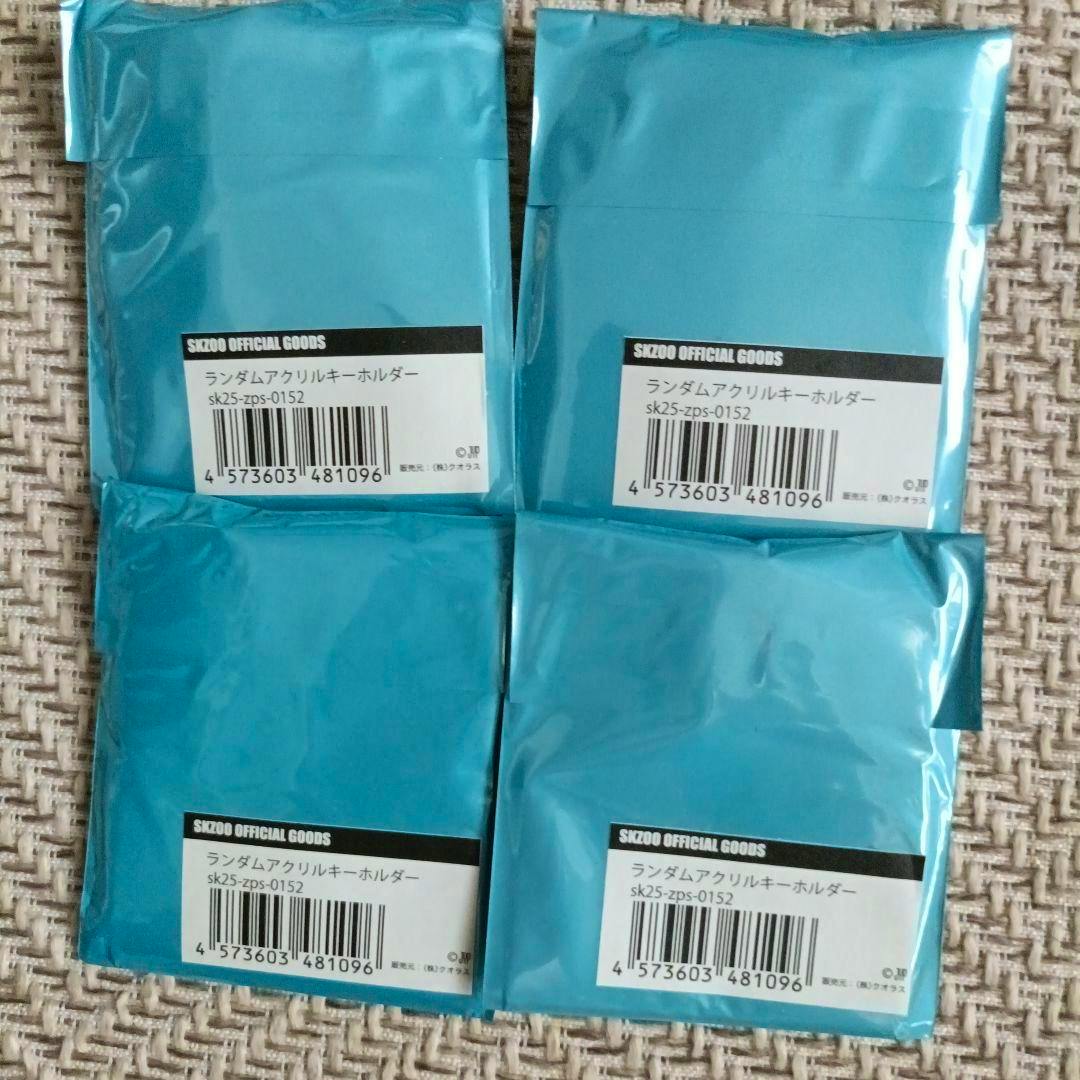 Four unopened blue foil packages labeled as Stray Kids random acrylic keychains with barcode stickers.