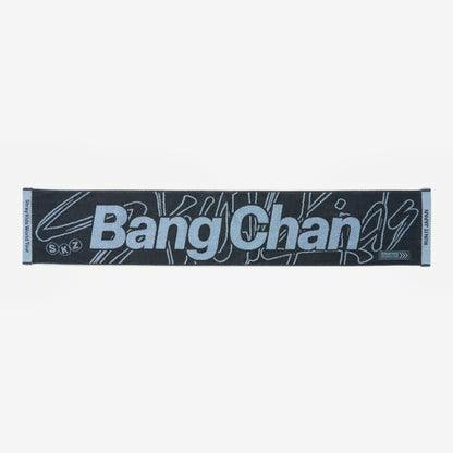 Flat lay of the Bang Chan muffler towel showing large light-blue "Bang Chan" text on a dark background.