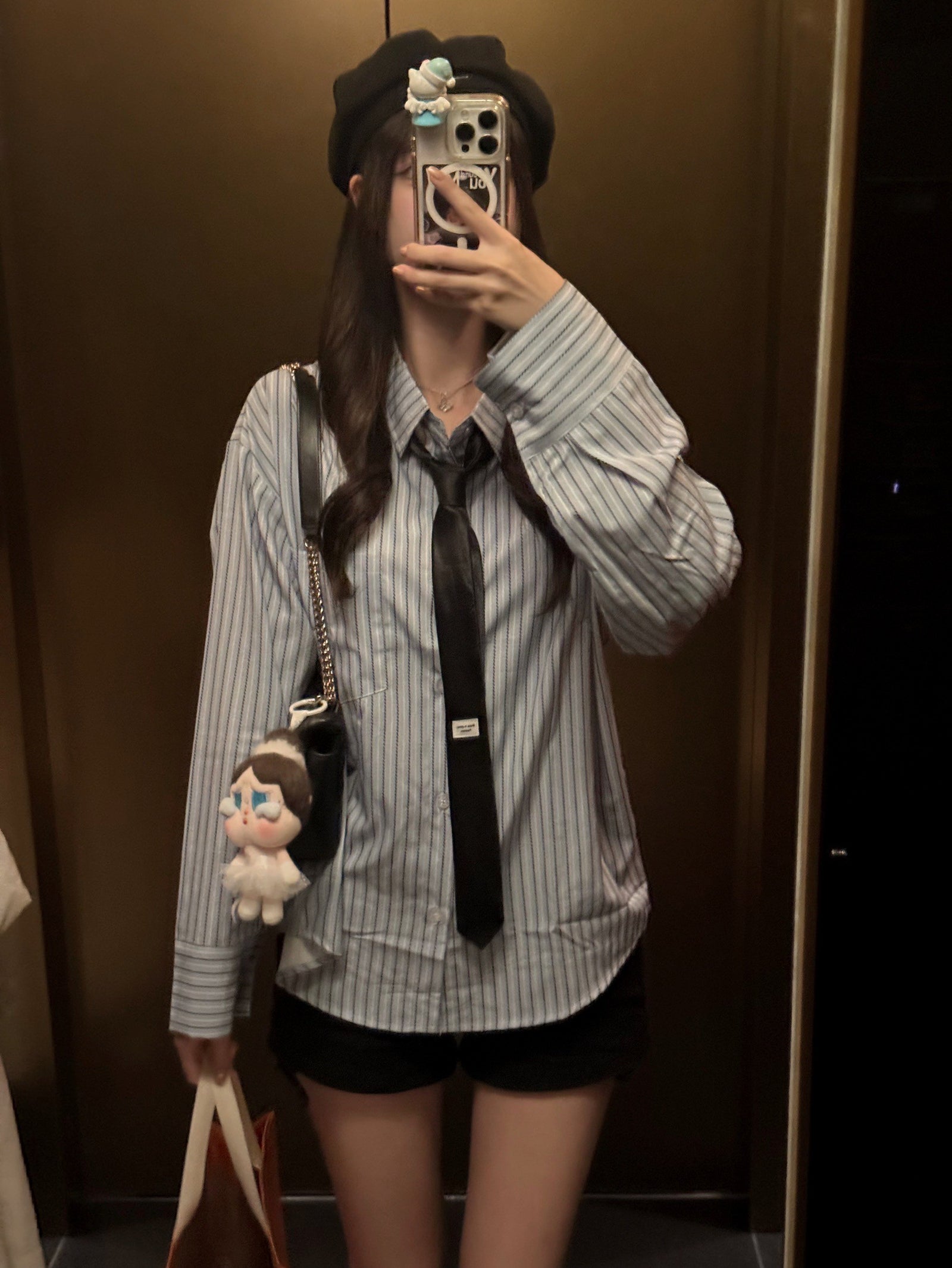 Mirror selfie of a person wearing a striped women's blouse with a black necktie.