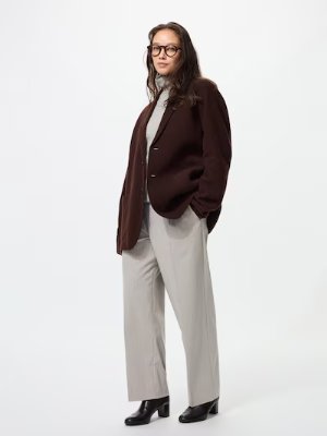 A model wearing the striped tuck wide pants in a light color paired with a dark jacket and heeled shoes.
