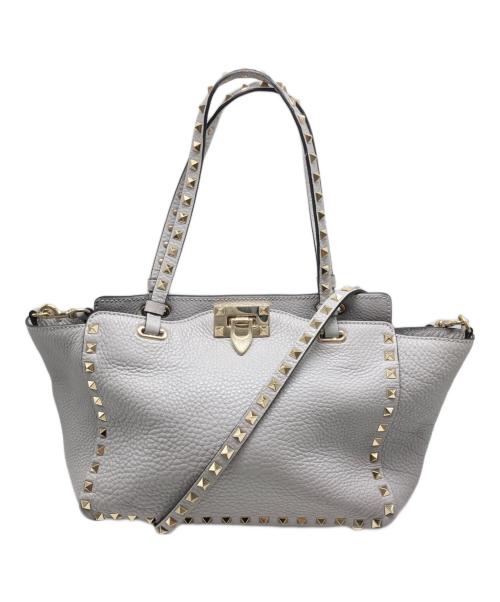 Gray cow leather studded shoulder bag with two top handles, a long shoulder strap across the front, and a central metal clasp.