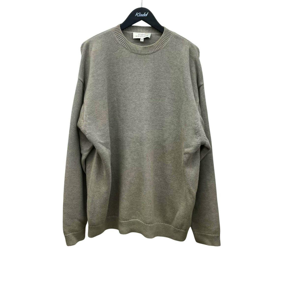 Front view of the STUDIO NICHOLSON wool sweater hanging on a hanger.