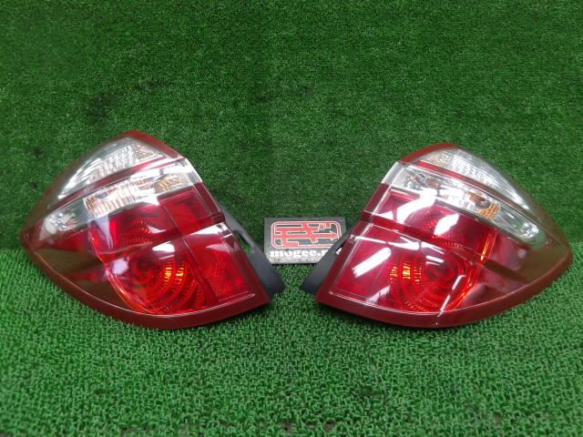 Pair of Subaru Legacy BP5 D-type rear tail lights (left and right) placed on green turf with a small sign between them.
