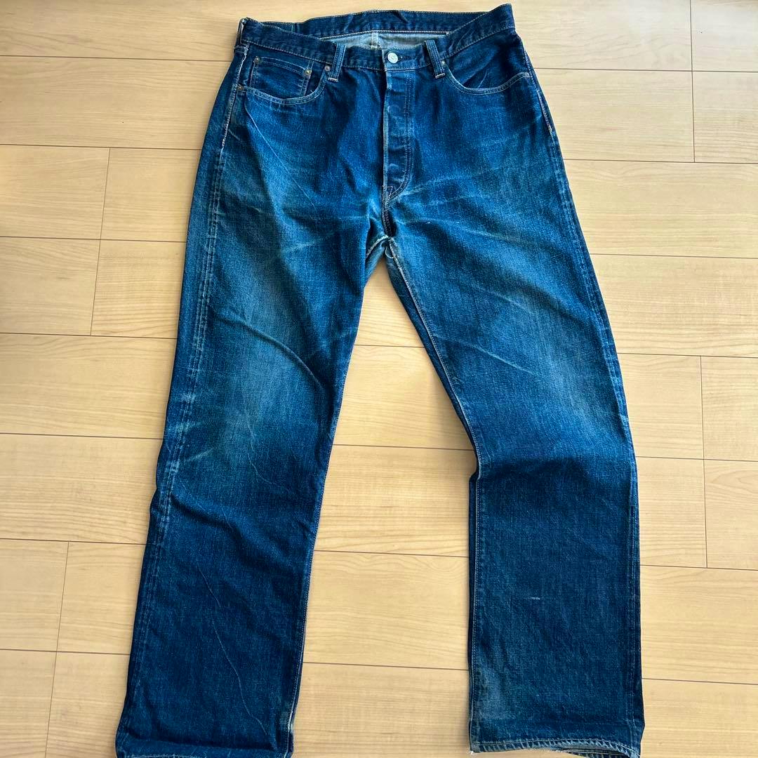 Front view of Sugar CANE 1947 men's jeans laid flat on a wooden floor showing full-length legs and front pockets.