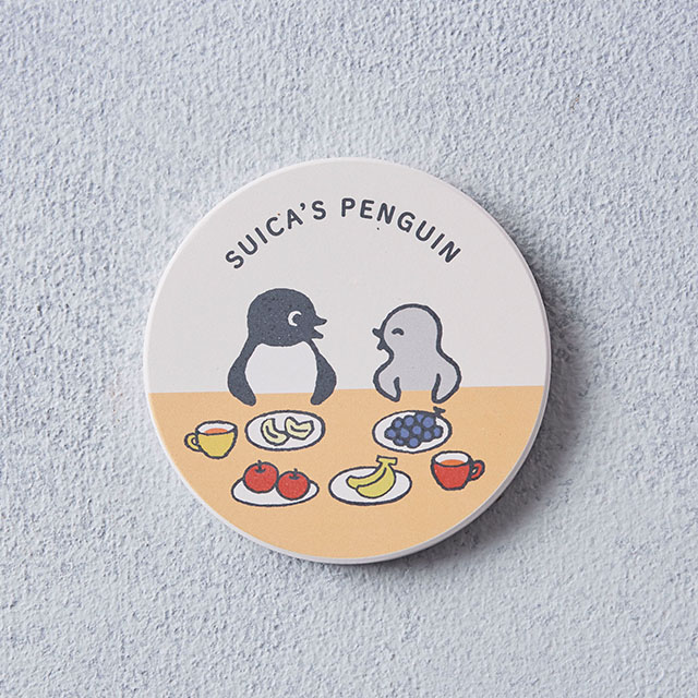 Round cork water-absorbent coaster showing Suica's Penguin and fruit illustrations on a two-tone background.