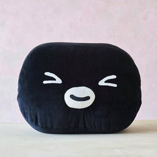 Front view of the Suica penguin hug-me cushion showing its black plush face with a white beak and smiling closed eyes.