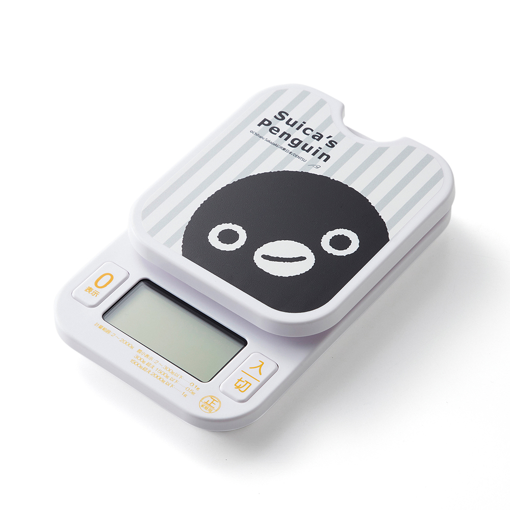 A white kitchen scale with the Suica penguin face printed on the weighing platform and a digital display.