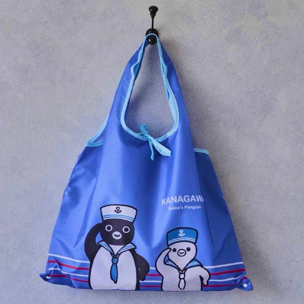 Blue reusable eco bag with Suica's Penguin sailor illustrations and "KANAGAWA" text hanging on a hook.