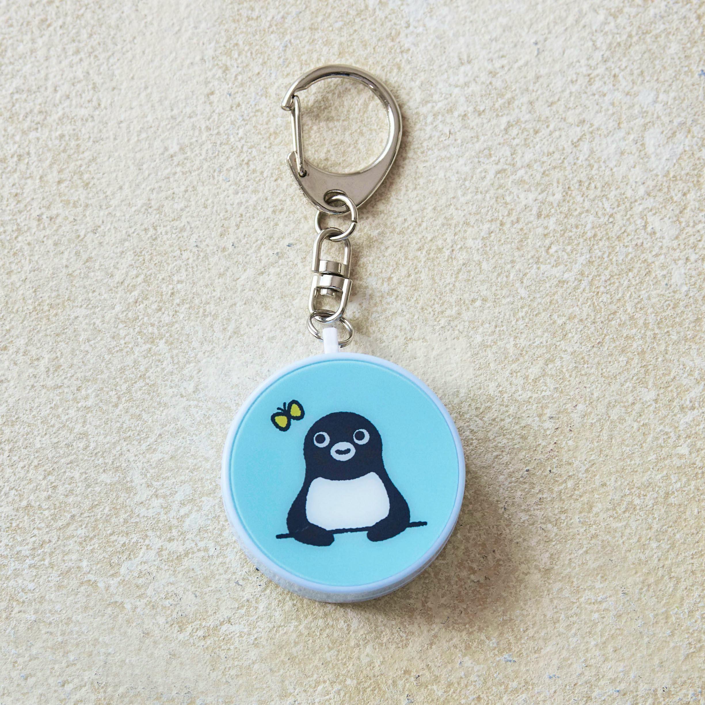 Front view of a blue round Suica penguin safety buzzer keychain showing the penguin design and the attached metal clasp and chain.