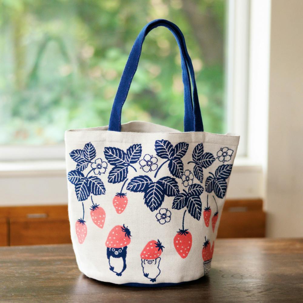 Cotton tote bag with navy handles and a printed strawberry pattern featuring Suica penguin characters on a white background.