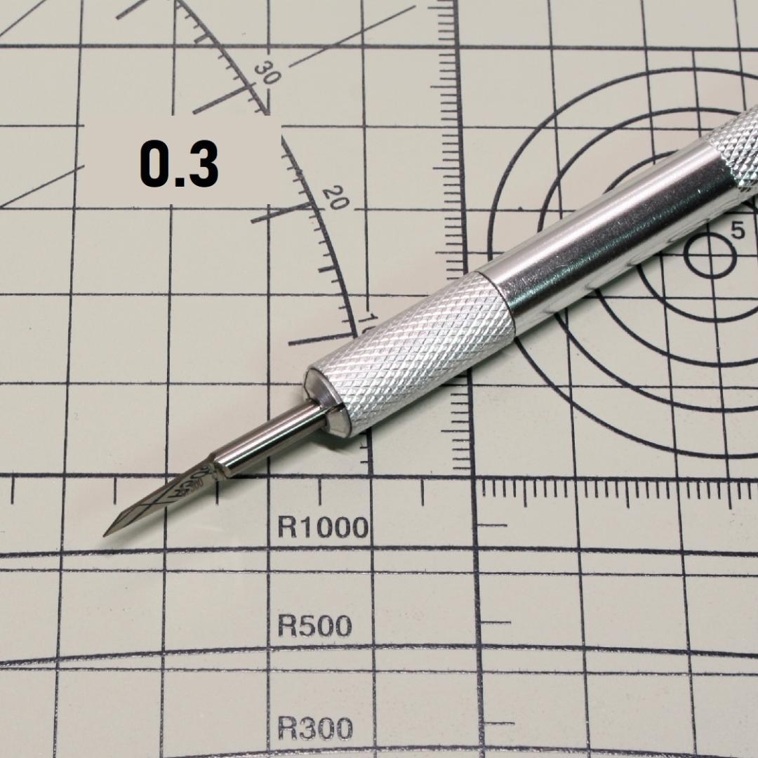 Close-up photo of the 0.3 mm chisel tip and knurled metal handle placed on a cutting mat.