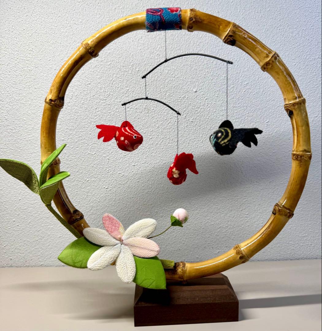 Bamboo ring display with three hanging fabric goldfish and a fabric flower on a wooden base.