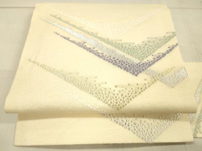 Folded nagoya obi (kimono sash) showing a cream-colored silk ground with abstract gold and silver thread pattern.