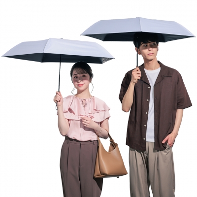 Two people holding the gray SUN DEFENCE sun umbrellas with a black inner lining, shown open.