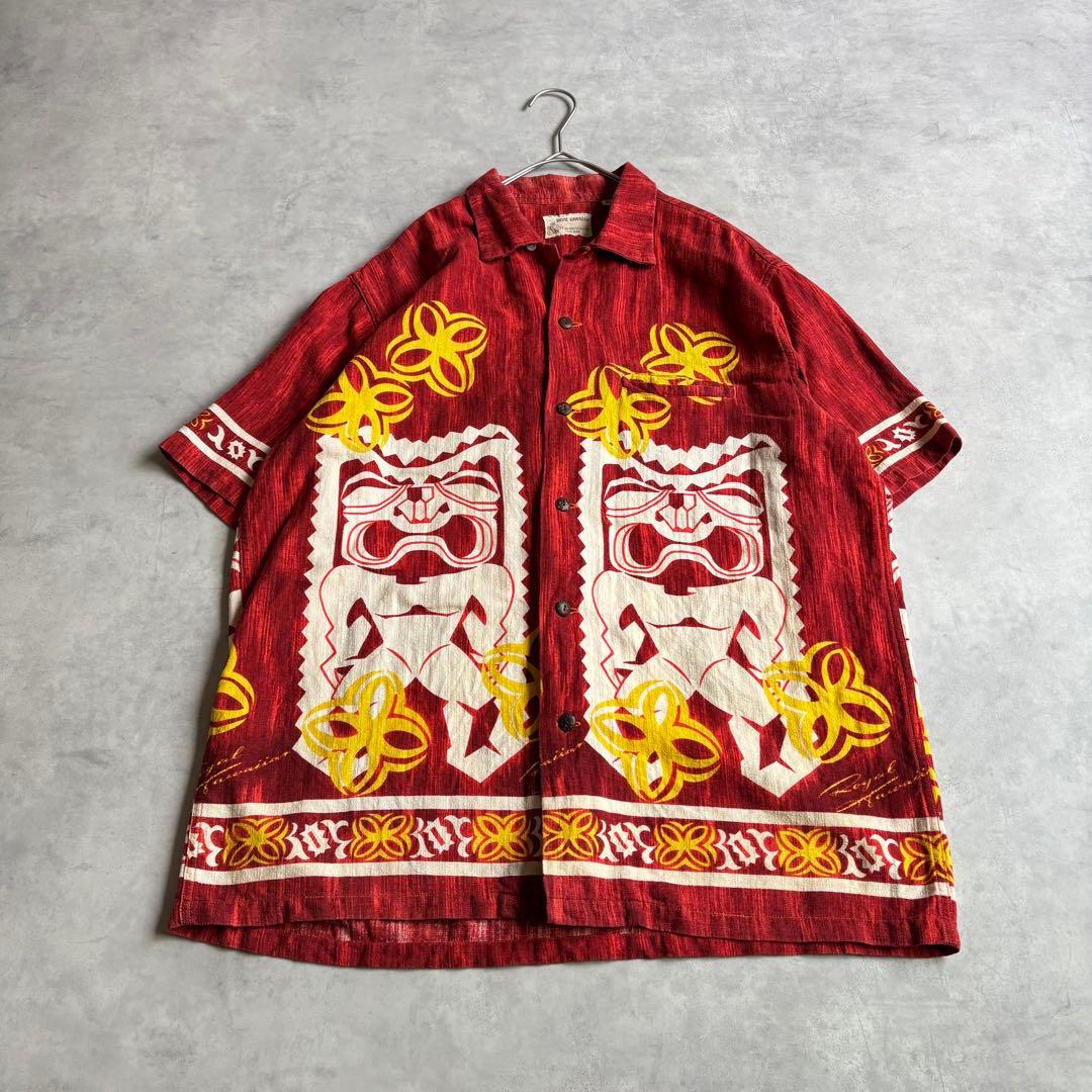 Red Sun Surf Royal Hawaiian vintage men's rayon aloha shirt with yellow tiki and flower prints laid flat on a gray surface.