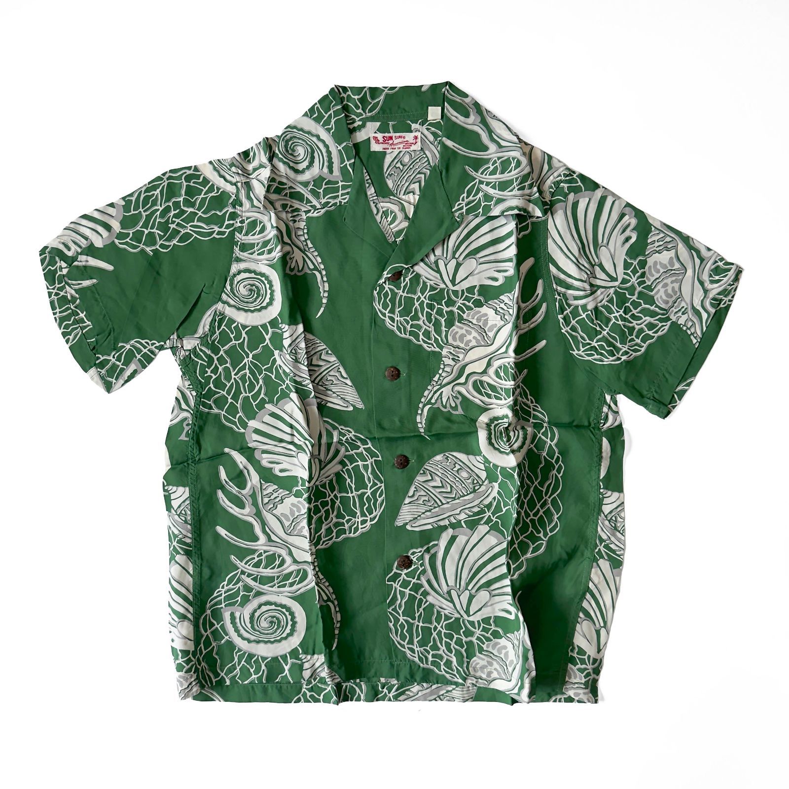 Green men's short-sleeve Hawaiian button-up shirt with white shell-border print laid flat on a white background.