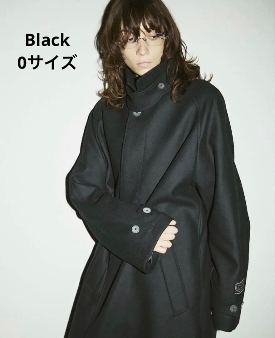 Woman modeling the black women's wool balmachan coat with high buttoned collar and buttoned cuffs.