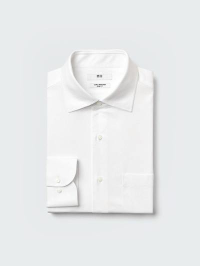 Folded white men's dress shirt (cotton) photographed on a light background.