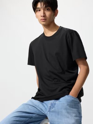 Male model wearing a black crew-neck T-shirt and jeans, seated.