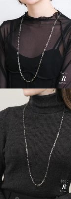 Model wearing the long stainless necklace chain shown in two views over black tops.