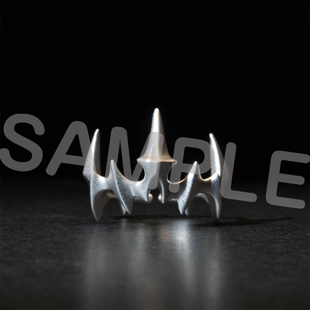 A silver motif ring photographed on a dark surface against a black background.