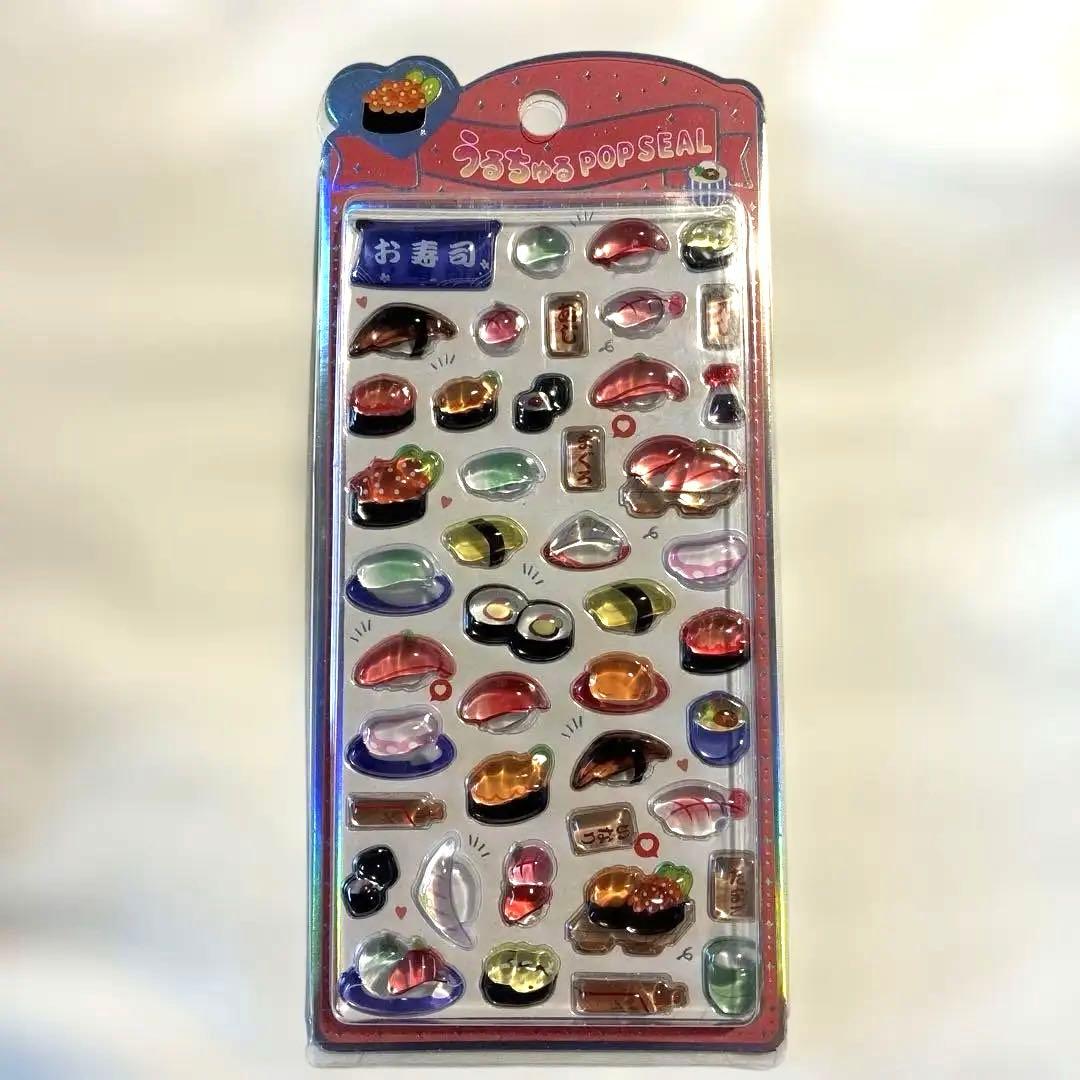 Front view of the packaged sushi-design plastic pop sticker sheet showing many small glossy sushi-shaped stickers.