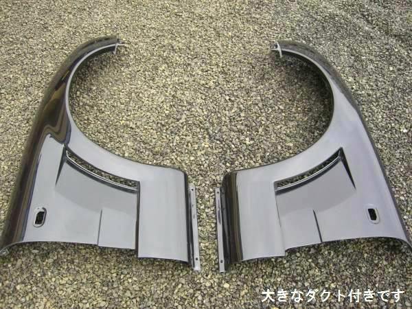 Pair of FRP 20mm wide fenders for a Cappuccino car laid on gravel.
