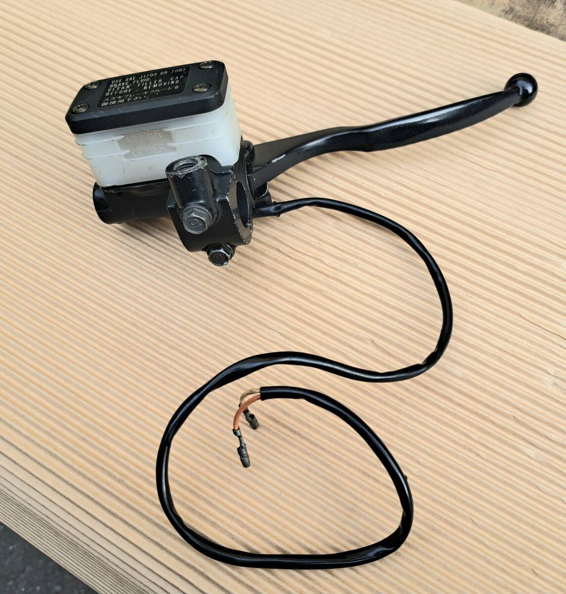 GSX400F brake master cylinder assembly with lever, fluid reservoir, and attached wiring on a corrugated surface.