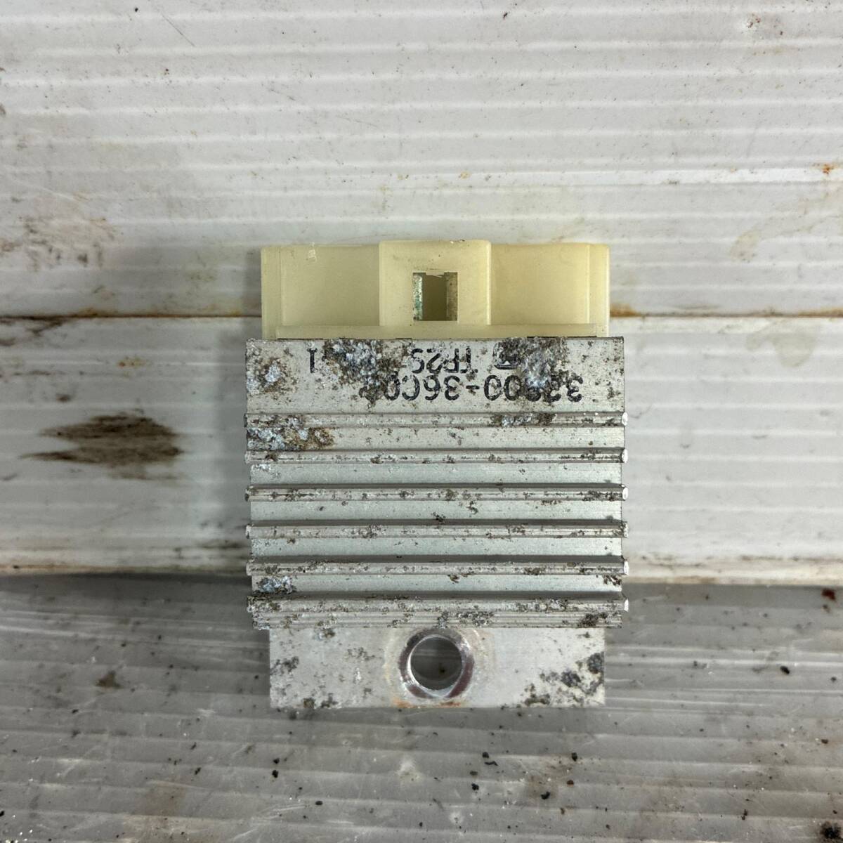 Used Suzuki car voltage regulator (CA1DB) showing metal cooling fins and a plastic connector.