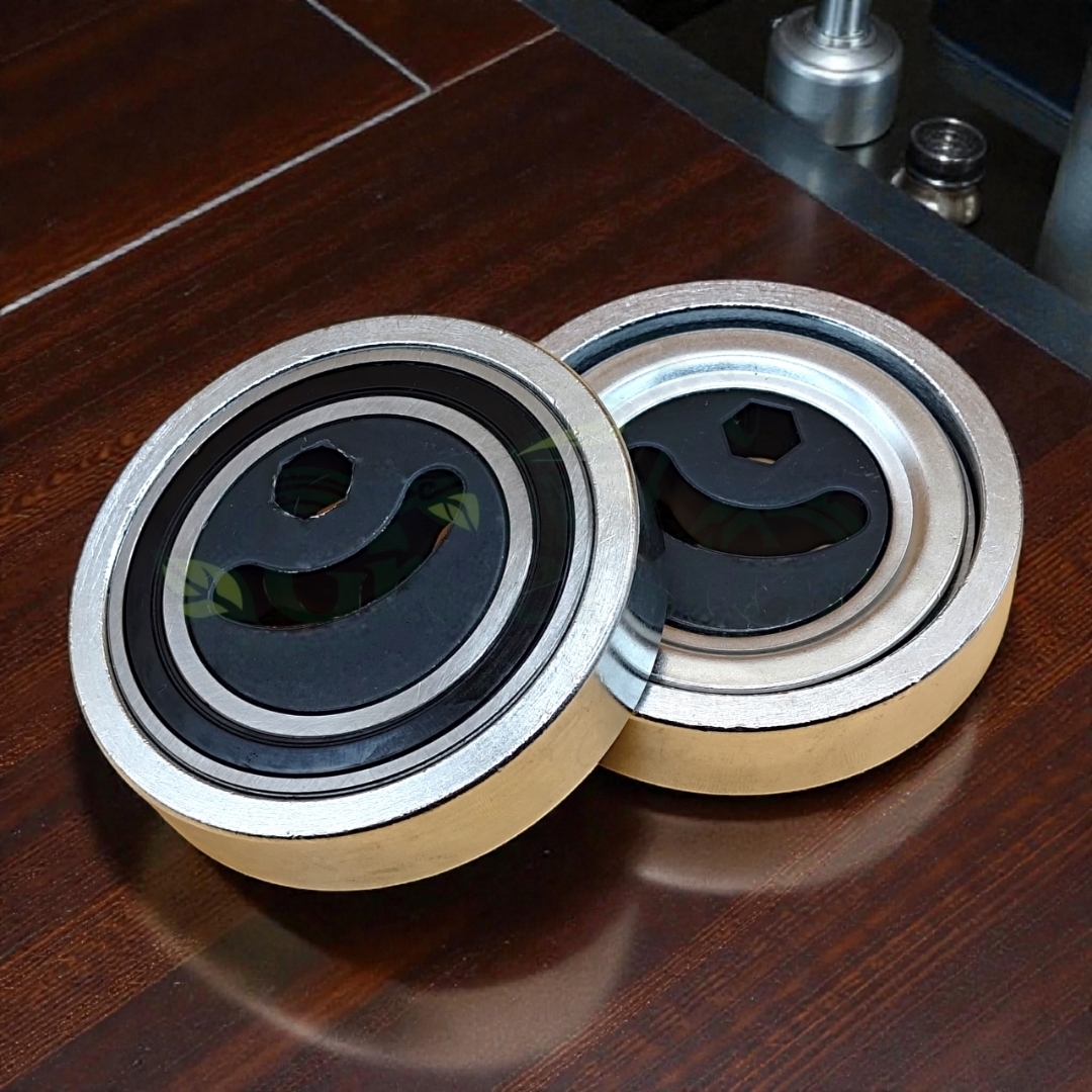 Two metal V-belt tensioner pulley bearings placed on a wooden surface.