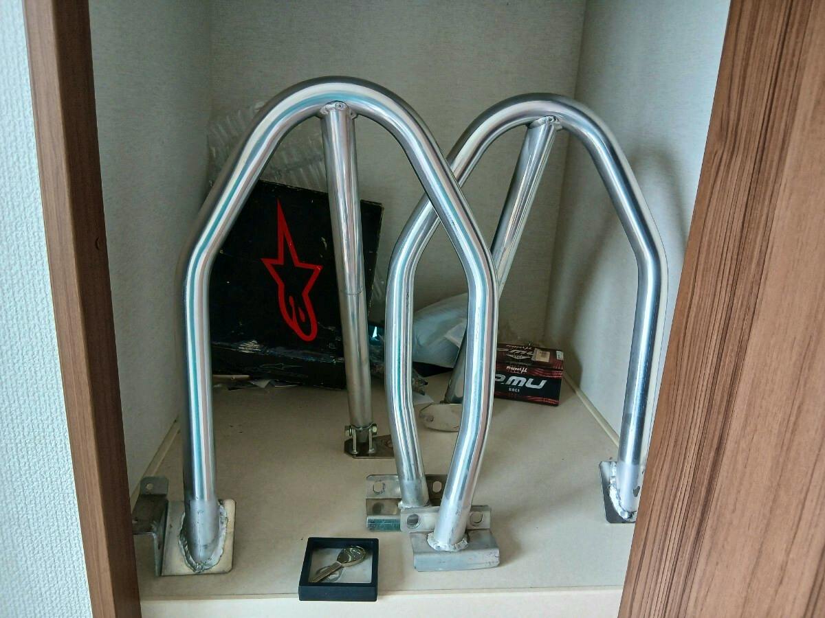 Silver vehicle roll bars with welded mounting plates displayed on a shelf.