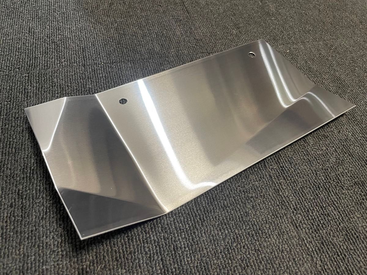Metallic engine heat shield plate for ZC33S Swift Sport placed on a dark carpet.