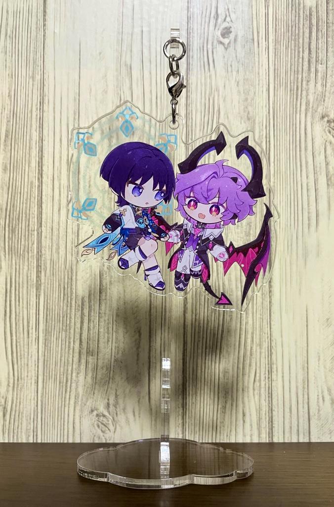 Clear acrylic decorative stand with a cloud-shaped base and a hanging acrylic charm showing two chibi characters.