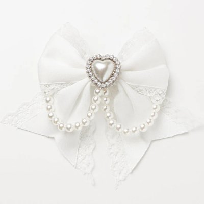 White bow hair clip with a central heart-shaped pearl surrounded by rhinestones and two draping faux-pearl chains on a white background.