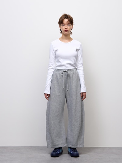 Model standing front wearing the women's gray sweat barrel pants with a white long-sleeve top against a plain background.