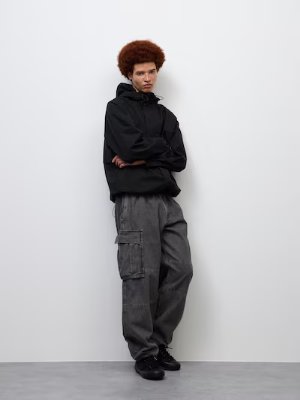 Model wearing a black full-zip hooded parka in an oversized fit against a white background.