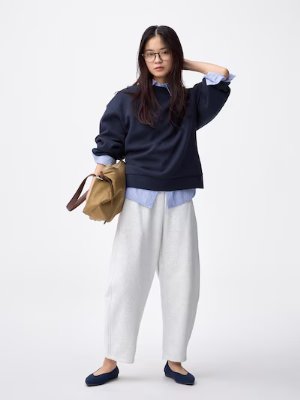 Model wearing the women's light gray ankle-length sweat pants styled with a navy top.