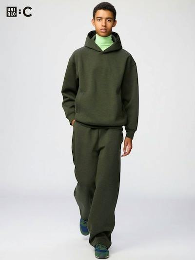 Model wearing dark green wide sweat pants and a matching hoodie, walking toward the camera.