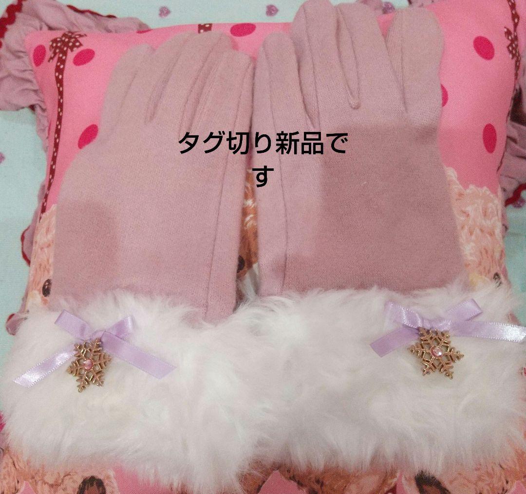 Pink-beige polyester gloves with white fur cuffs and snowflake charms laid flat on a pink cushion.