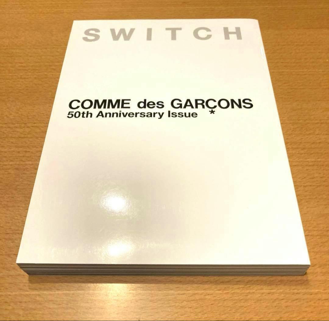 Front cover of the SWITCH COMME des GARÇONS 50th Anniversary Issue magazine placed on a wooden surface.