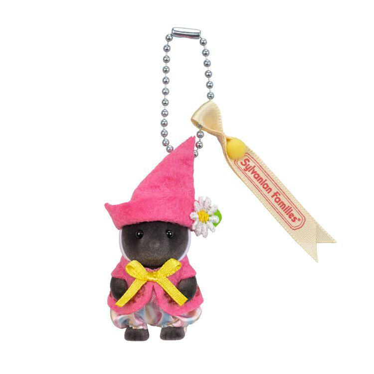Close-up of the Sylvanian Families keychain showing the mole baby figure wearing a pink triangular hat, yellow bow, patterned pants, and an attached ball-chain with a ribbon tag.