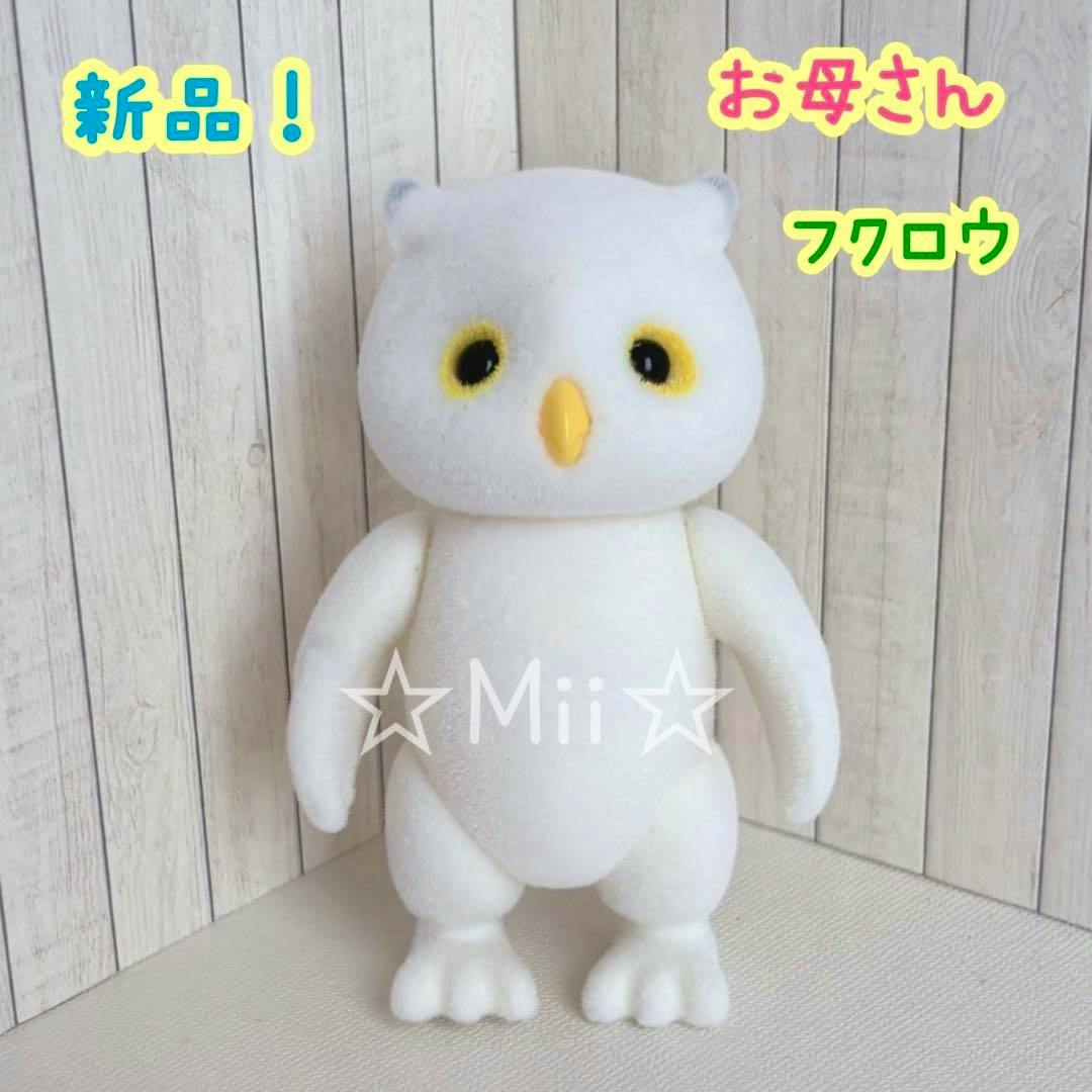Front view of a white Sylvanian Families owl mother plush toy standing against a wood-panel background.