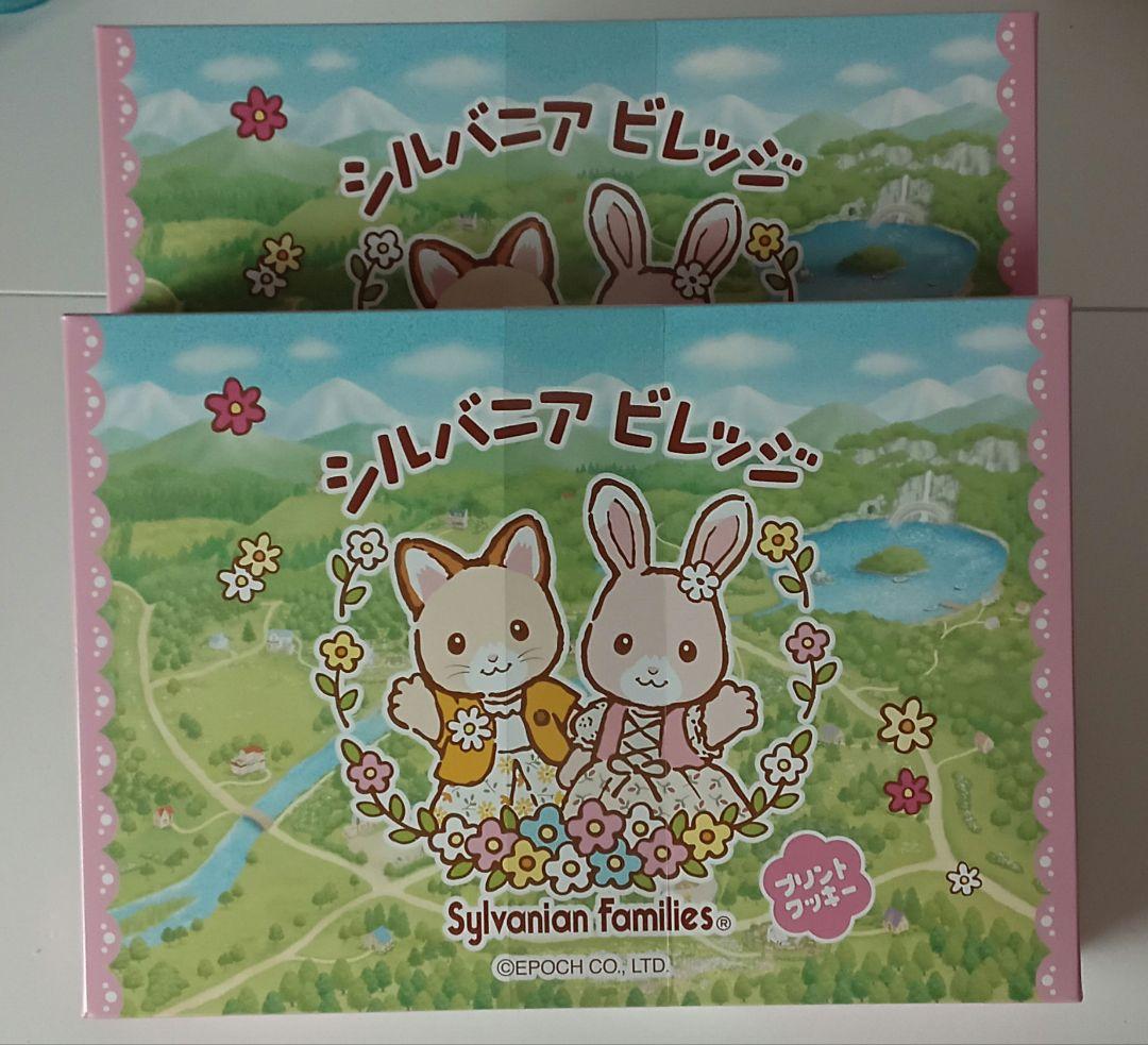 Boxed Sylvanian Families Village limited printed cookies showing rabbit and cat characters on a green landscape packaging.