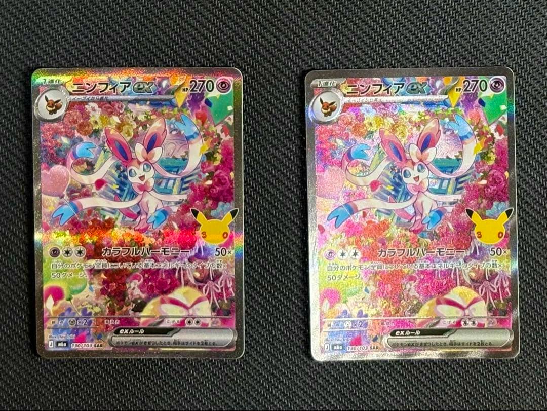 Two Sylveon ex (ニンフィアex) holographic trading cards displayed side-by-side on a dark textured surface.
