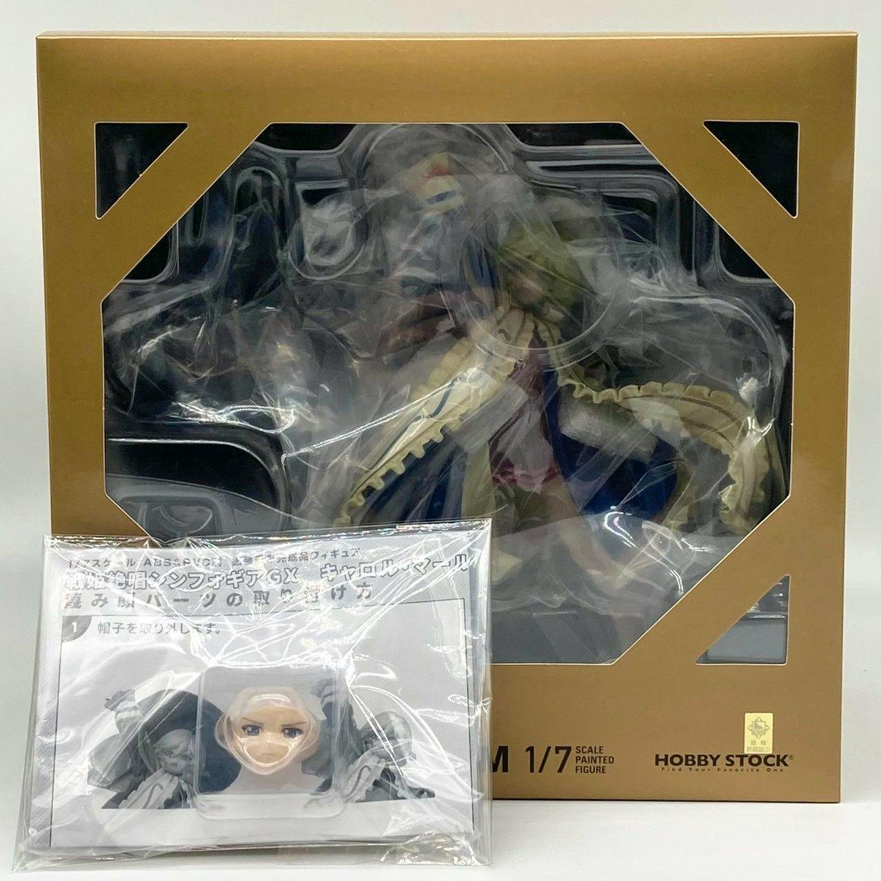 Boxed HOBBY STOCK 1/7 scale 戦姫絶唱シンフォギアGX キャロル・マールス・ディーンハイム figure in original packaging with an extra face part visible.