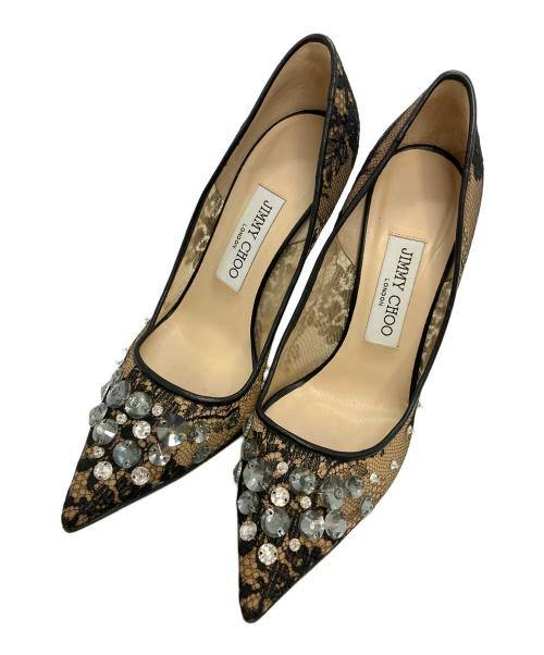 Close-up of a pair of pointed-toe heel pumps with lace overlay and crystal embellishments.