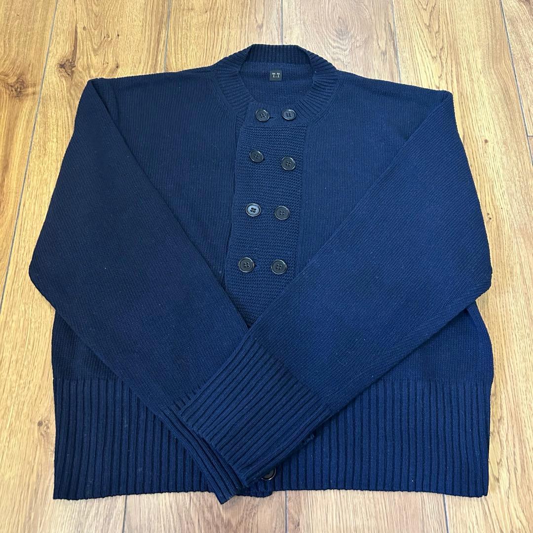Navy double-breasted cardigan sweater laid flat on a wooden floor.
