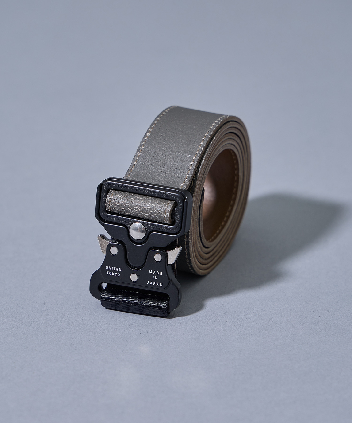 A rolled cow leather belt featuring a tactical-style metal buckle on a plain background.